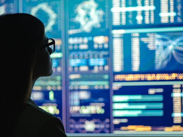 A silhouette of a person looking at digital display