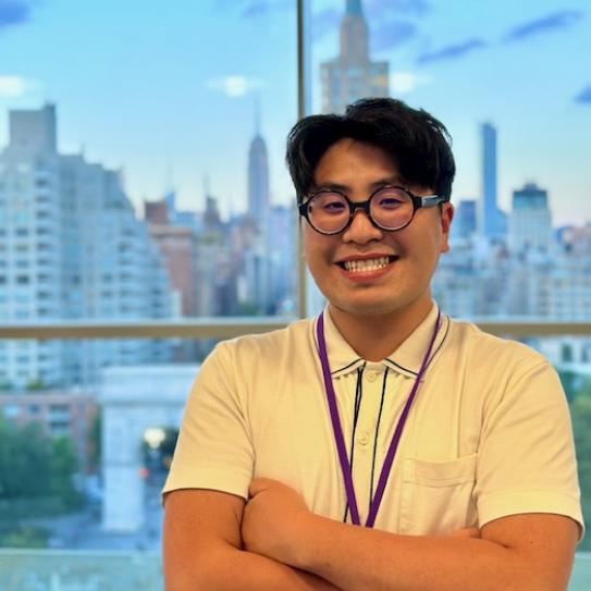 Jason Le is standing in front of a window with a smile on his face